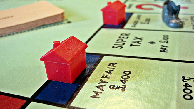 A person playing monopoly with a house on mayfair and parklane.