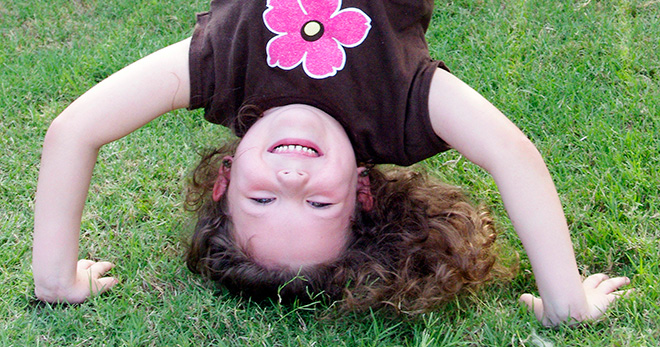 a smiling girl standing on her head