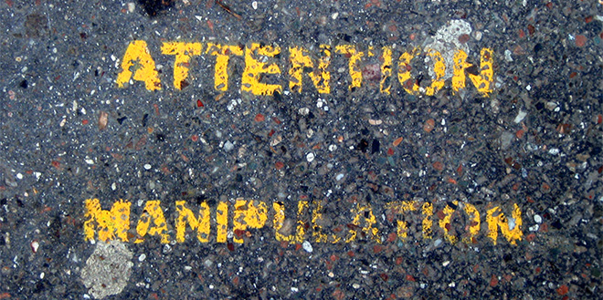ATTENTION MANIPULATION stencil painted on asphalt